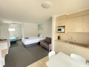 a small room with a bed and a kitchen at Araluen Motor Lodge in Batemans Bay