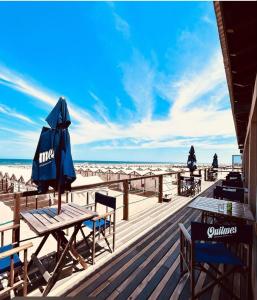 a boardwalk with tables and an umbrella on the beach at Duplex del Parque y Balneario in Necochea