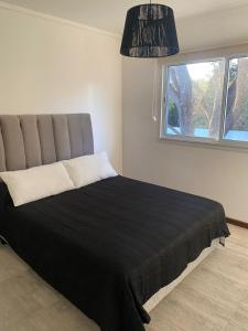 um quarto com uma cama preta e uma janela em Duplex del Parque y Balneario em Necochea