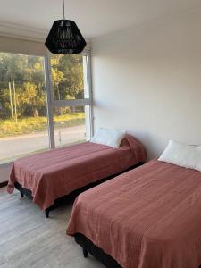 two beds in a room with a window at Duplex del Parque y Balneario in Necochea