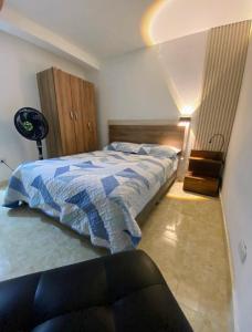 a bedroom with a bed with a blue and white comforter at Apartamentos en el Norte de cali in Cali
