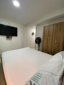 a bedroom with a white bed and a flat screen tv at Apartamentos en el Norte de cali in Cali