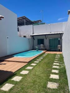 a backyard with a swimming pool and grass at Casa de praia Jauá in Camaçari