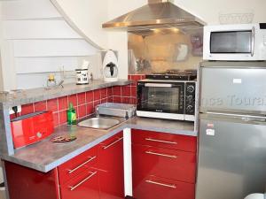 eine Küche mit roten Schränken und einem Kühlschrank aus Edelstahl in der Unterkunft Gîte Montlouis-sur-Loire, 2 pièces, 2 personnes - FR-1-381-488 in Montlouis-sur-Loire