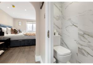 łazienka z toaletą i łóżko w pokoju w obiekcie Brand New Spacious & Chic Studio -Central Location w Londynie