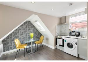 a kitchen with a table and chairs and a washer and dryer at Brand New Spacious & Chic Studio -Central Location in London