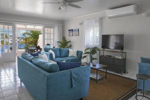 a living room with blue couches and a television at The Anchorage #5 a 3 bedroom Waterfront Condo in Rodney Bay condo in Gros Islet