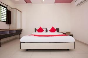 Un dormitorio con una gran cama blanca con almohadas rojas. en Hotel O Capital O Sai Icon Residency, en Titwala 15 fotos más