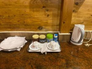 un plateau avec des tasses et des soucoupes ainsi qu'une cafetière dans l'établissement TREKKING TRAILS ECO STAY, à Kalpatta