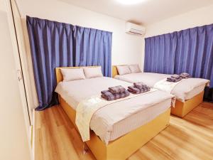 東京にあるRosenheim Tokyo Shinjuku Okuboの青いカーテンが備わる客室のベッド2台