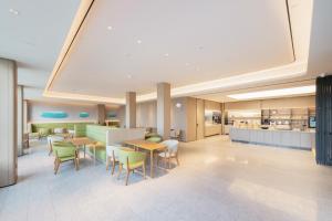 um restaurante com mesas e cadeiras e uma cozinha em All Seasons Hotel - Jiaozhou Jiaodong Airport Liwang Road em Jiaoxian