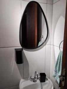 a bathroom with a sink and a mirror on the wall at Milton Bandeira flat in Viçosa