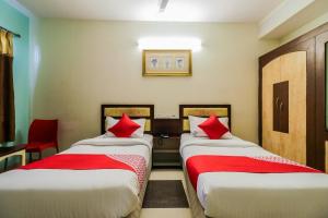 2 bedden in een kamer met rode kussens bij Parnasala Princely in Rājahmundry