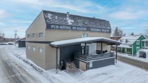 a building with snow on the ground next to a street at Hôtel St-Alexis in Saint-Raymond