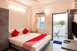 a bedroom with a bed with red pillows and a window at D' Jade in Hyderabad