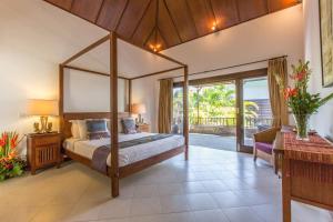a bedroom with a canopy bed and a patio at Villa Sedap Malam Seminyak by Best Deals Asia Hospitality in Seminyak