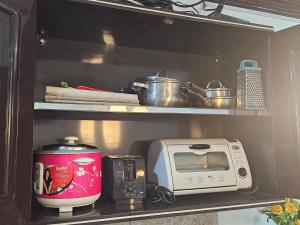 a kitchen shelf with a microwave and a toaster at 3MC Guest House in Butuan