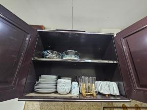 a cupboard with plates and utensils in a kitchen at 3MC Guest House in Butuan