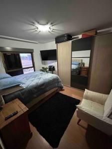 ein Schlafzimmer mit einem Bett, einem Sofa und einem Stuhl in der Unterkunft Apartamento Central COM 02 BOX de garagem in Caxias do Sul
