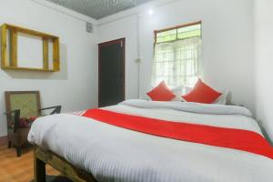 a bedroom with a large bed with red pillows at OYO Bell's Bigxa Homestay in Cherrapunji