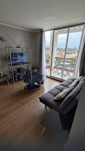 a living room with a couch and a large window at Excelente depto equipado completo, a pasos del mar in La Serena