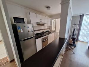 a kitchen with a stainless steel refrigerator and white cabinets at Excelente depto equipado completo, a pasos del mar in La Serena