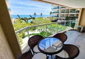balcón con mesa, sillas y vistas al océano en Vista Mar em Villa del Sol Residences - unidade autônoma, en Río de Janeiro