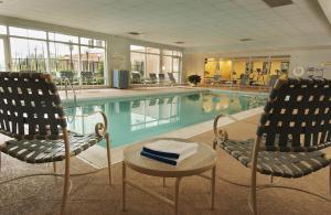 a swimming pool with two chairs and a table in a hotel at Hampton Inn Dulles/Cascades in Sterling