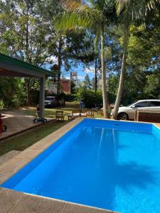 une grande piscine bleue dans une cour arborée dans l'établissement La Casa Del Lago, à Posadas