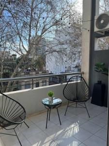 2 Stühle und ein Tisch auf einem Balkon mit einem Baum in der Unterkunft Dúplex en Flores para 4 personas in Buenos Aires