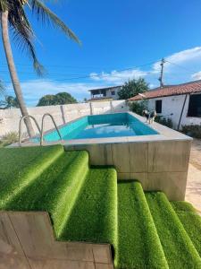 a swimming pool in a yard with green grass at Casa Encanto da Barra in Fortim