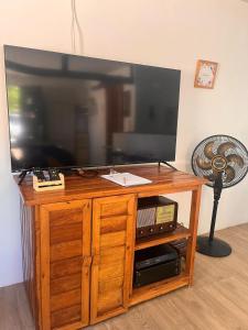 a flat screen tv on a wooden entertainment center at Casa Encanto da Barra in Fortim