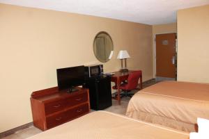 ein Hotelzimmer mit einem Bett und einem Schreibtisch mit einem TV in der Unterkunft Fairview Inn & Suite in Jonesboro