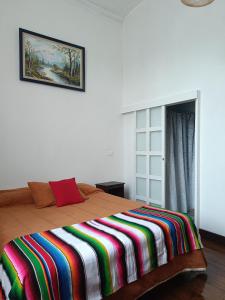 Un dormitorio con una cama con una manta de colores. en Hostal Tulio Porteño, en Valparaíso