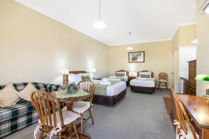 a hotel room with two beds and a couch at Ballina Heritage Inn in Ballina