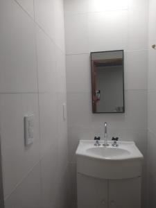 Baño blanco con lavabo y espejo en CABAÑAS CHASCOMUS 2024 en Chascomús