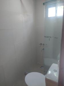 y baño blanco con aseo y ducha. en CABAÑAS CHASCOMUS 2024 en Chascomús