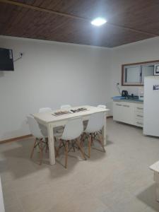 cocina con mesa blanca y sillas blancas en CABAÑAS CHASCOMUS 2024 en Chascomús