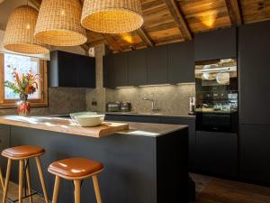 a kitchen with black cabinets and brown stools at Chalet Penthouse Luxe à Méribel - Concierge, Spa, Parking - FR-1-613-41 in Méribel