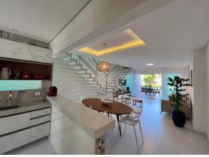 a kitchen and dining room with a table and stairs at Bela casa condominio beira mar praia dos carneiros in Tamandaré