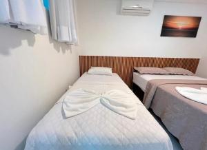 two beds in a small room with a bow on them at Bela casa condominio beira mar praia dos carneiros in Tamandaré