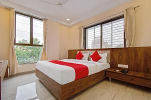 ein Schlafzimmer mit einem großen Bett mit roten Kissen in der Unterkunft Super Capital O Hotel C Tara in Shirdi