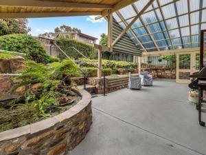 a conservatory with a stone wall and a patio at Wanderers Retreat in Jindabyne