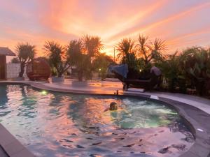 a person swimming in a pool with a sunset in the background at ปีกไม้วิลล่าb2 