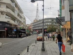 Una mujer caminando por una calle en una ciudad en PERSEUS 3 BEDROOM Apartment 102 en Lárnaca