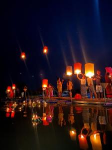 a group of people holding lanterns in the water at night at ปีกไม้วิลล่าb2 