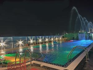 una piscina por la noche con una fuente en THE PELICAN BEACH RESORT en Mandarmoni