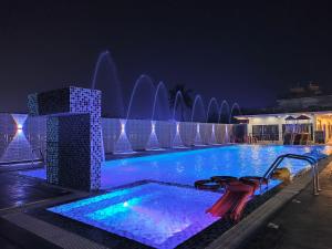 a swimming pool with a fountain at night at THE PELICAN BEACH RESORT in Mandarmoni