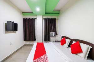 Schlafzimmer mit einem Bett mit roten Kissen und einem TV in der Unterkunft OYO Flagship 62748 Hotel Zeenat in Jammu