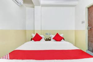 1 dormitorio con 1 cama grande con almohadas rojas en OYO Suraj Residency, en Warangal